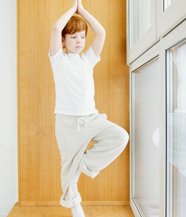 Child in a tree yoga pose showing balance and concentration.