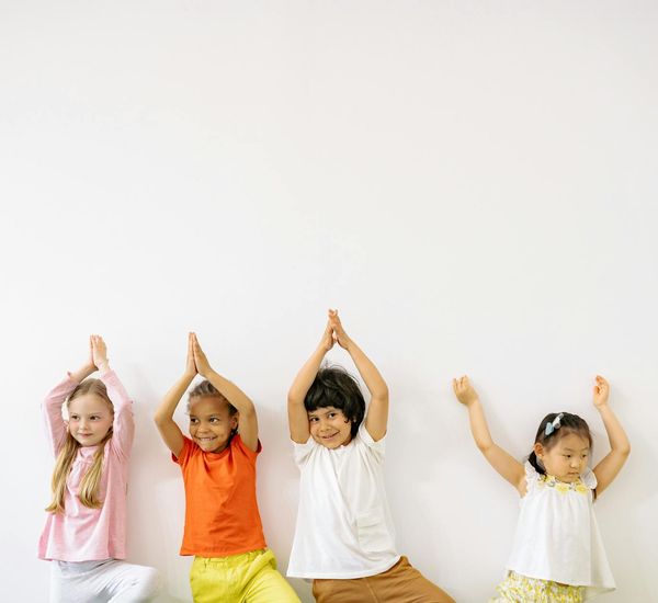 Happy children doing a simple yoga pose in a bright room.