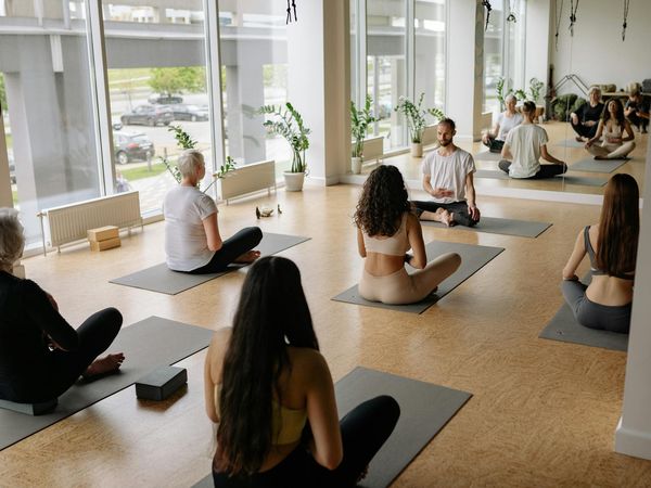 Instructor showing a yoga pose to a small group of attentive children.